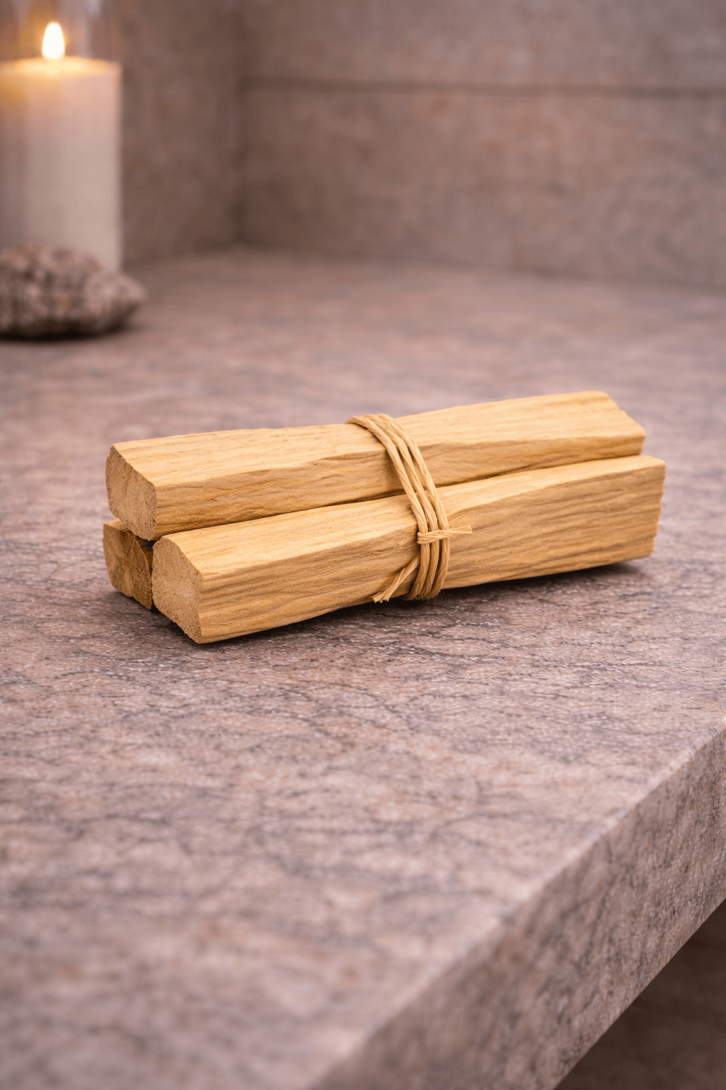 Wooden sticks tied with twine on a stone surface with a candle in the background