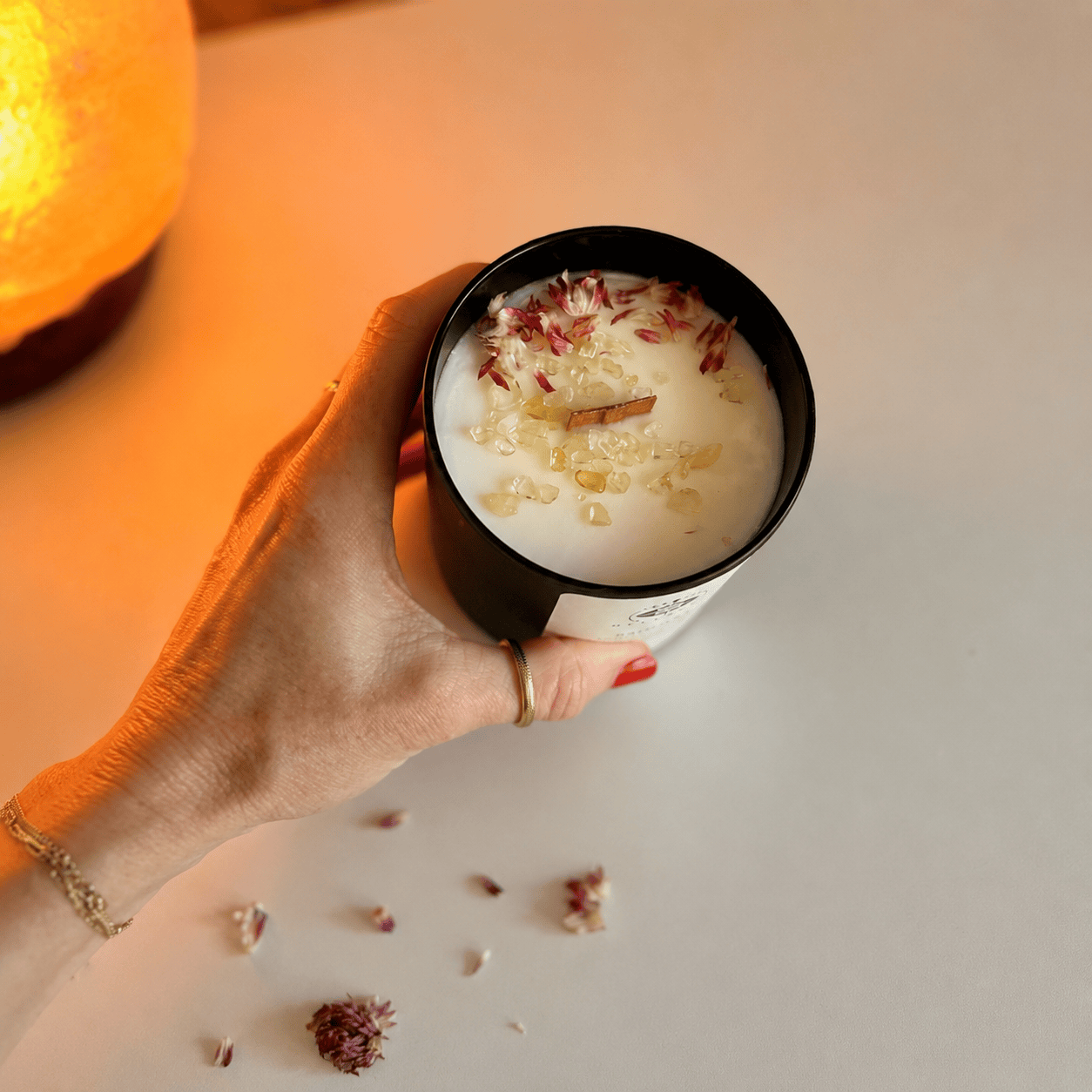 Hand holding BellaVee Radiant citrine crystal candle with wooden wick and floral details