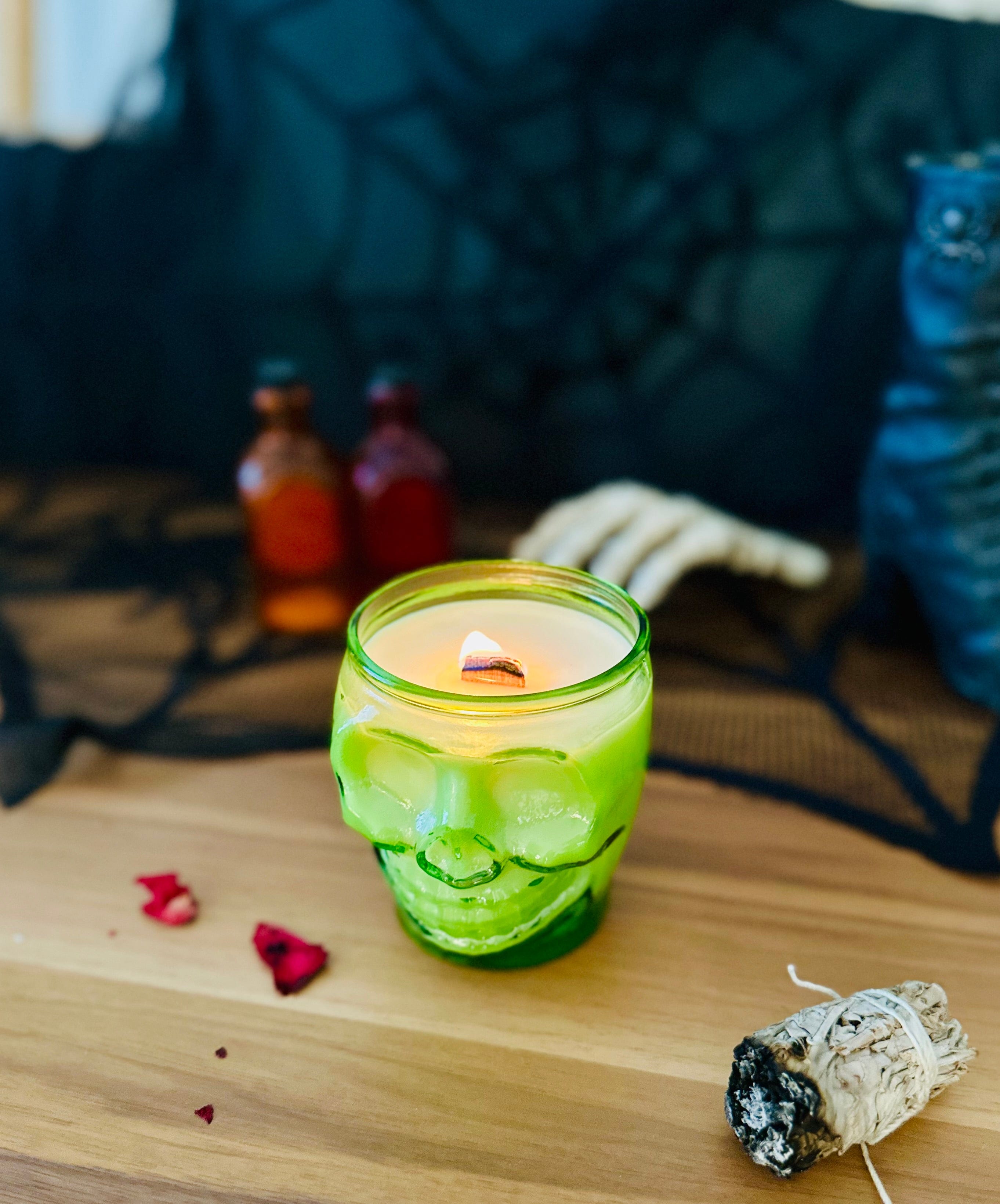 Spooky neon green skull candles lit with black background and dried rose petals