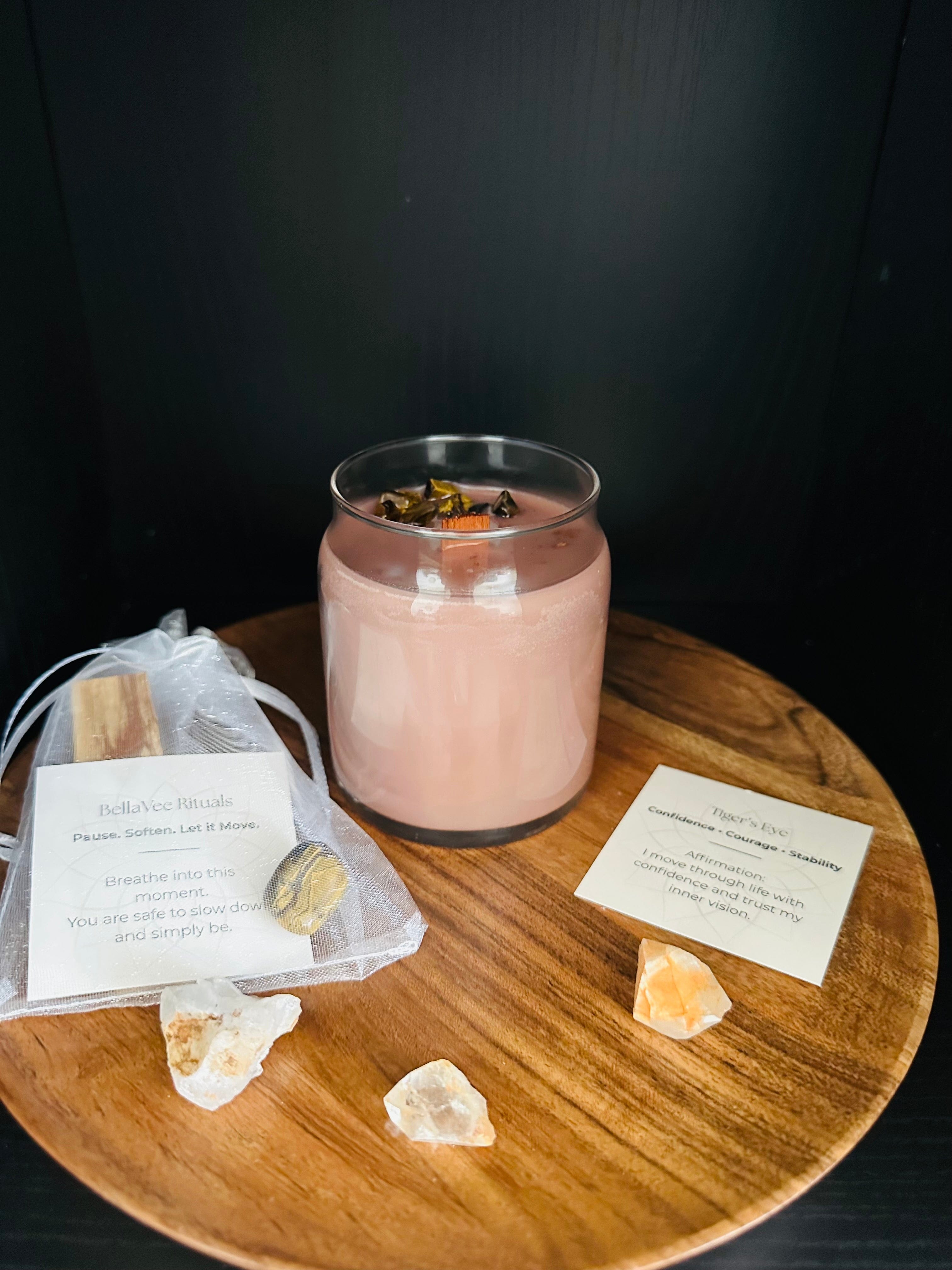 Pink crystal candle on a wooden table with crystals and cards on a dark background