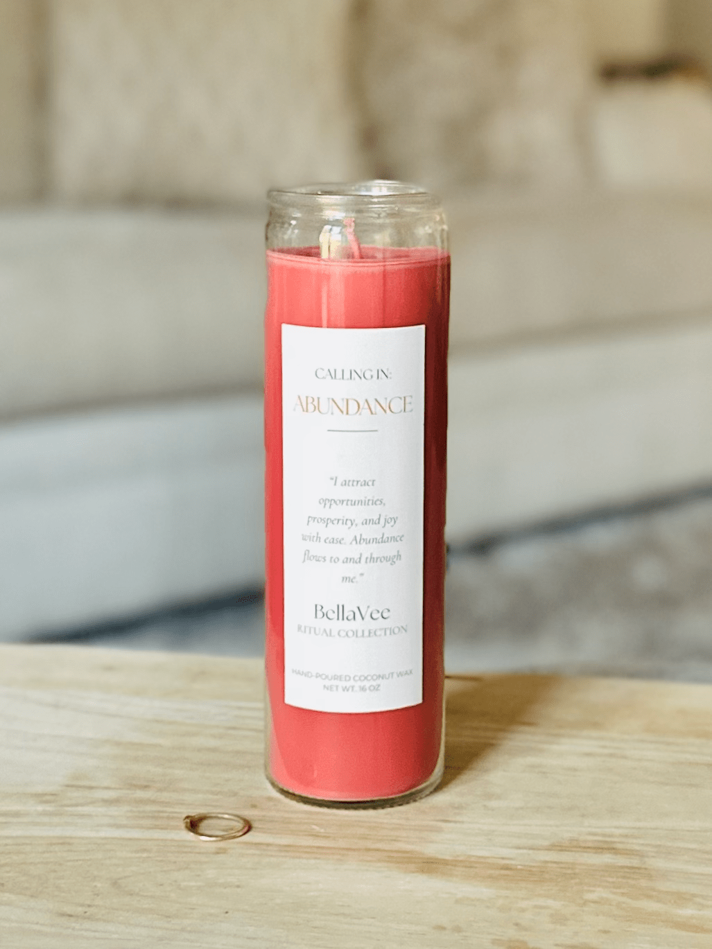 Close-up of the Calling In: Abundance Ritual Candle in a bold red wax with white label.