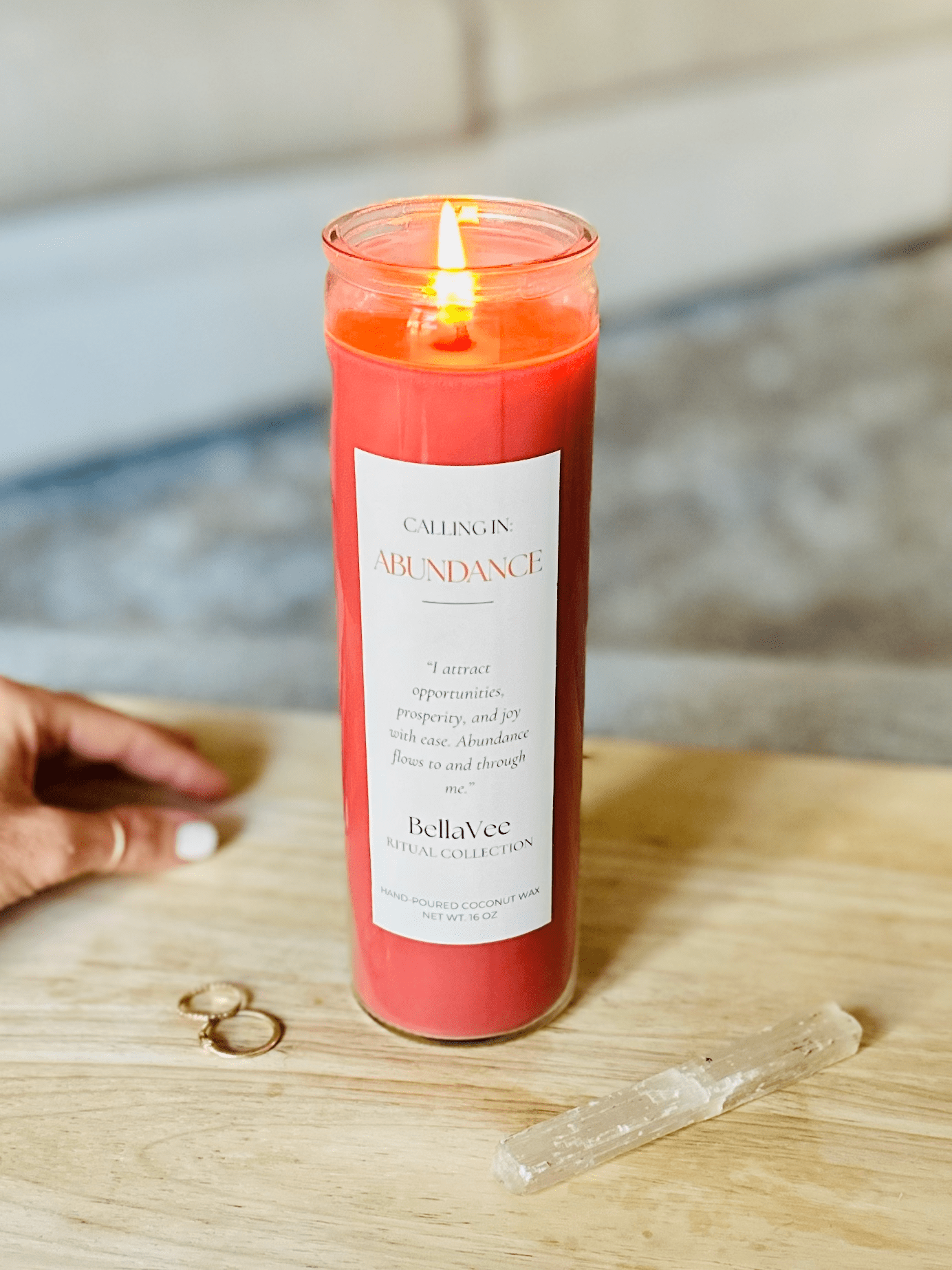 Calling In: Abundance candle glowing with flame during ritual use, highlighting its deep red tone.