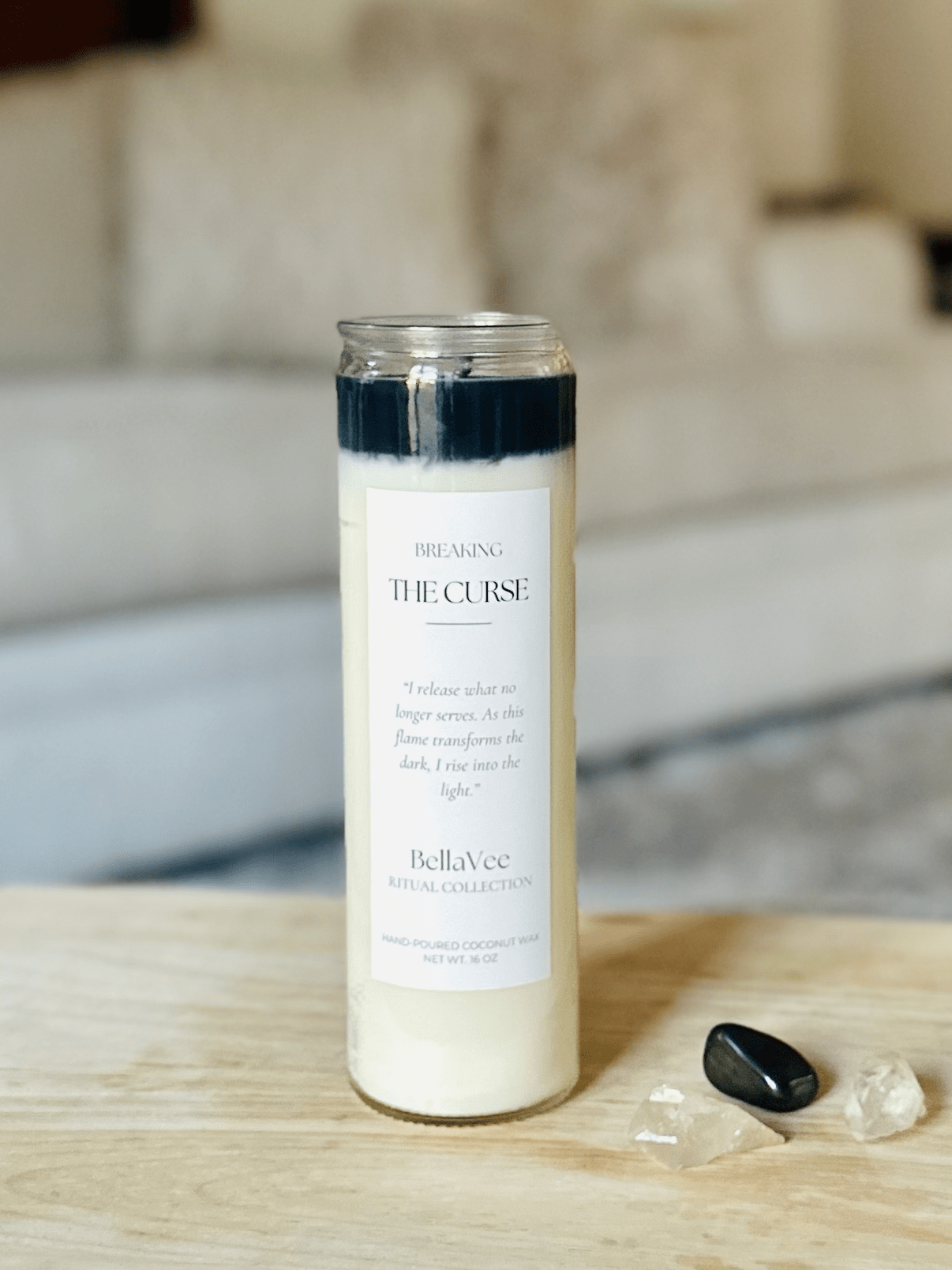 Close-up of the Breaking The Curse Ritual Candle with black and ivory wax in a clear glass container.