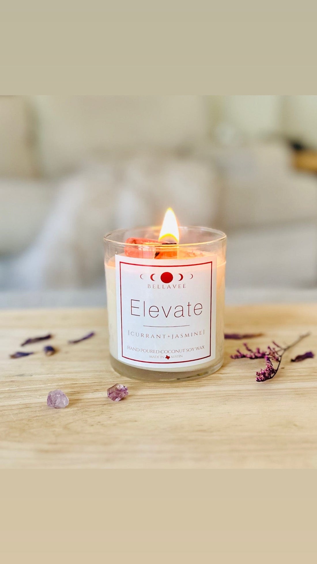 Lit elevate amethyst crystal candle with dried botanicals and crystals surrounding it