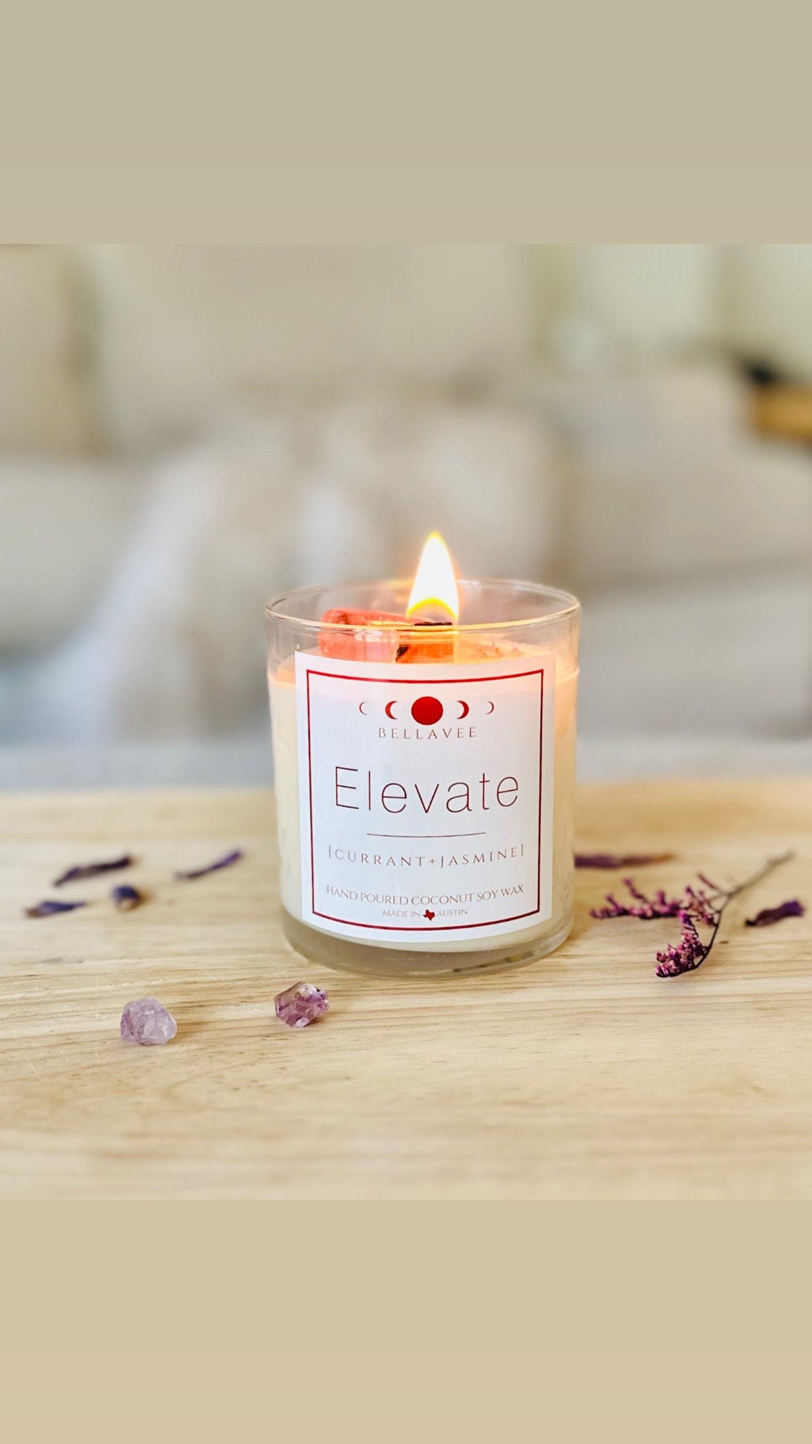 Lit elevate amethyst crystal candle with dried botanicals and crystals surrounding it