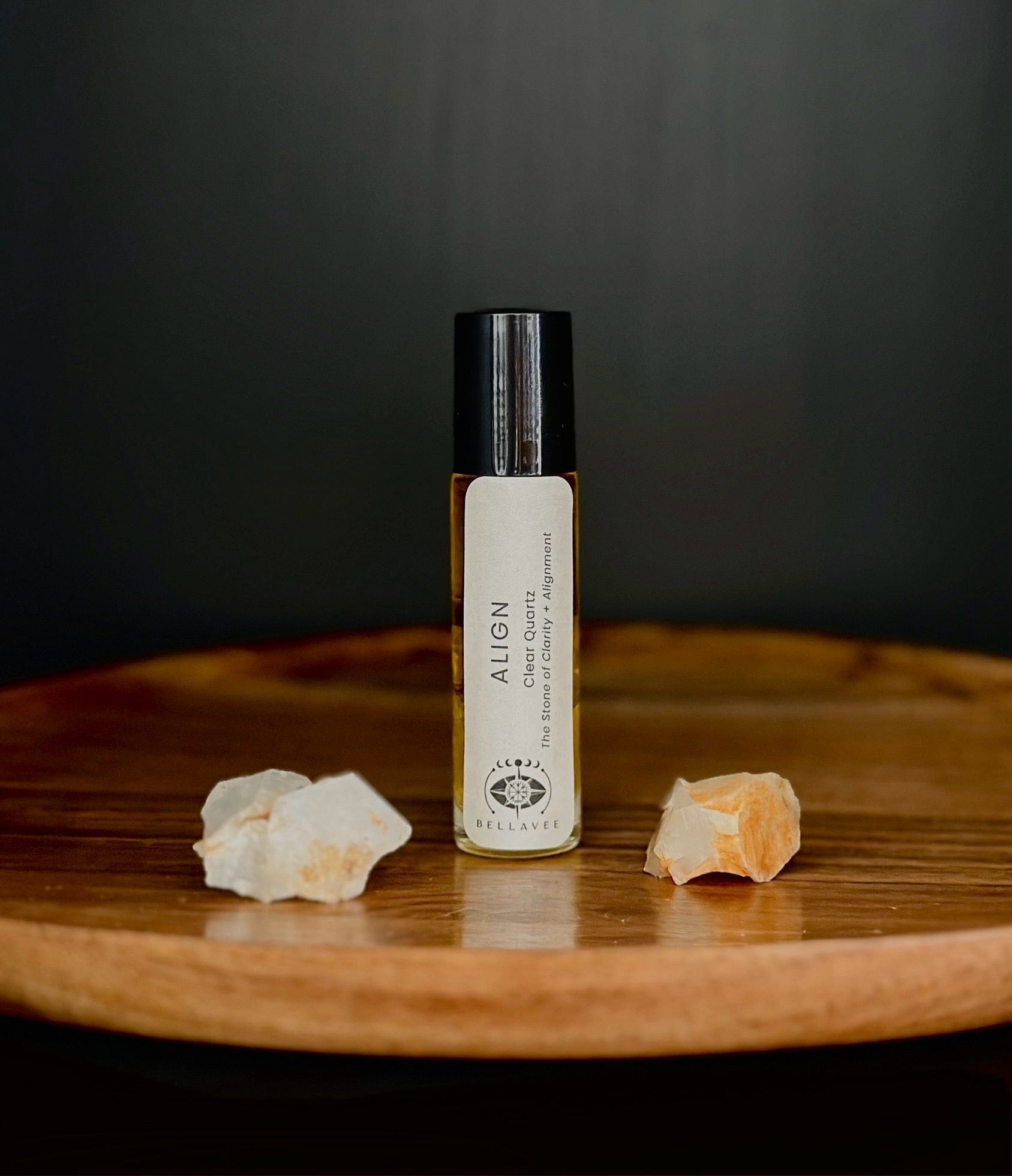 Crystal-infused essential oil roll-on labeled “Align” with Clear Quartz stones on a wooden surface.