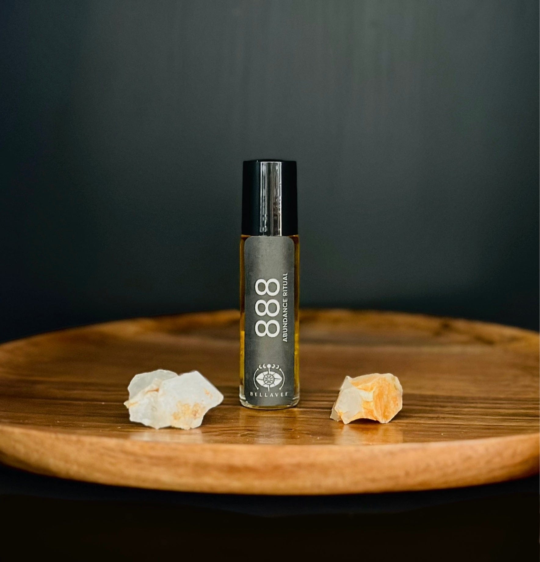 Crystal-infused essential oil roll-on labeled “888” with Citrine stones on a wooden surface.