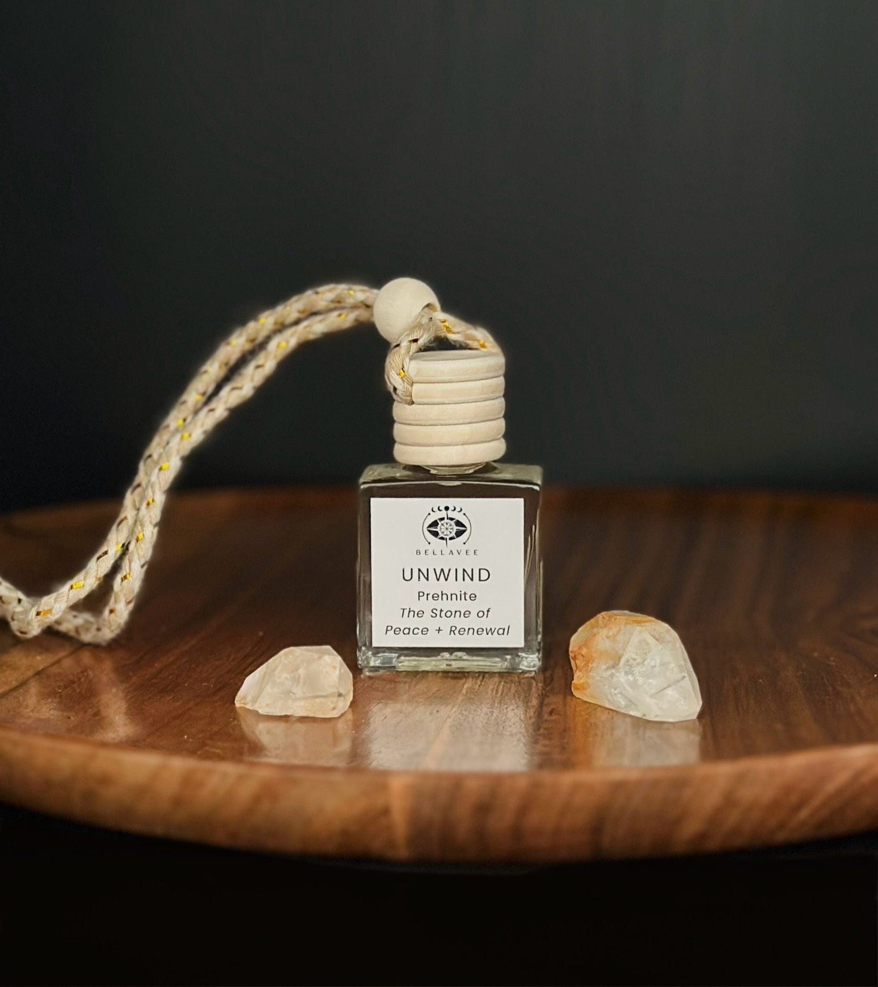Crystal-infused diffuser labeled “Unwind” with Prehnite stones on a wooden surface.