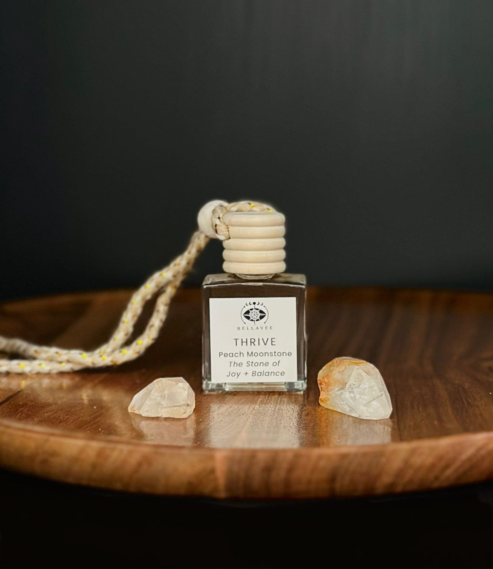 Crystal-infused diffuser labeled “Thrive” with Peach Moonstone stones on a wooden surface.