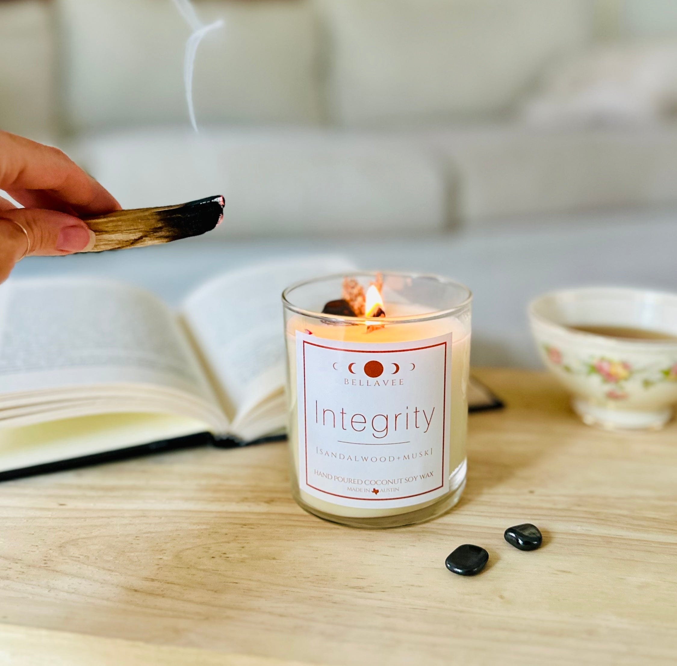 Hematite crystal candle with lit palo Santo cleansing and purifying the candle. Topped with dried botanicals and wooden wick for longer burn time