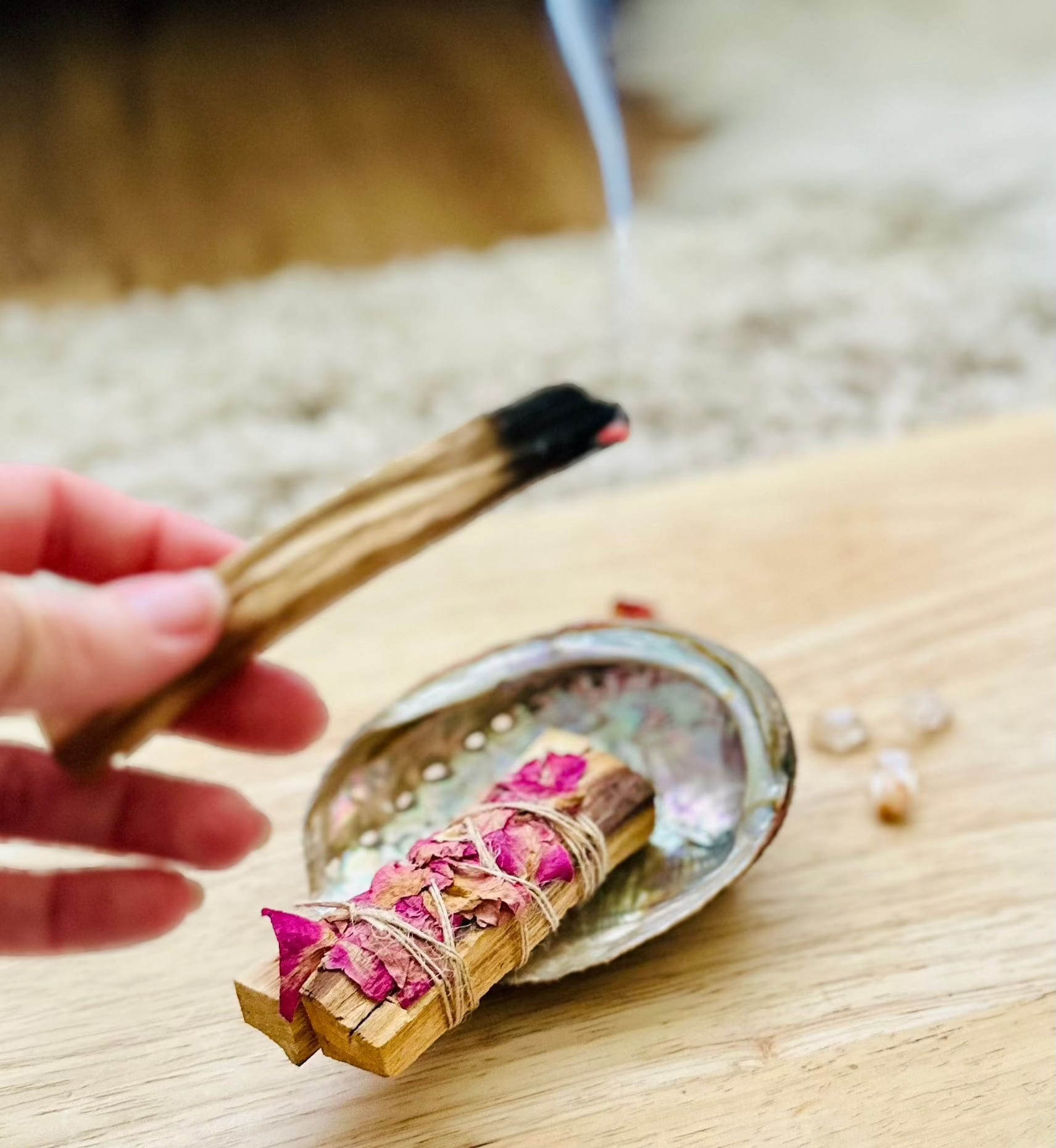 Smoke rising from Palo Santo as it’s held over the ritual box items.