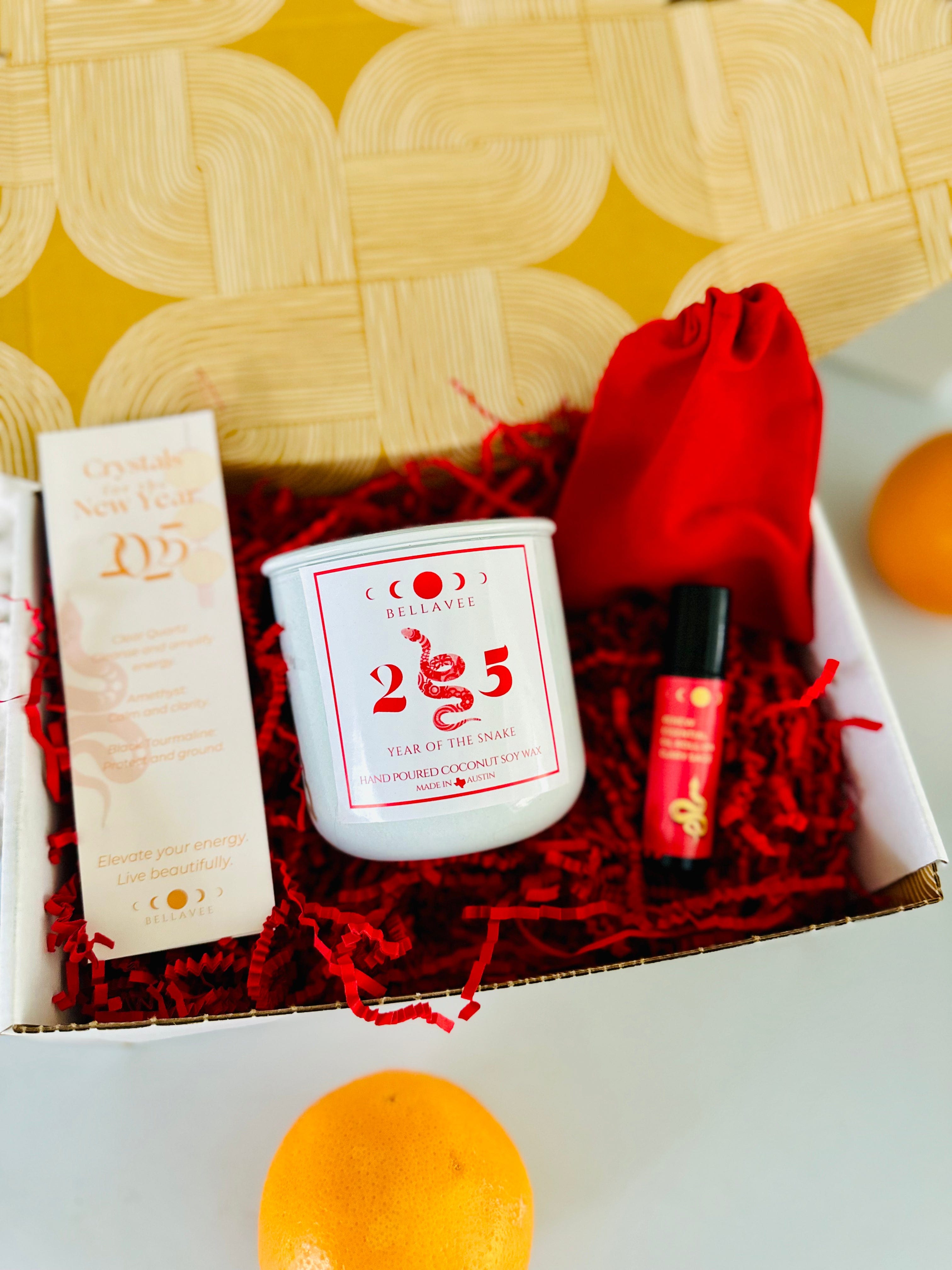 Lunar New Year Year of the Snake Gift Box with Snake Candle, Clary Sage Essential Oil Roll-On, and 2025 Crystal Bookmark in a red velvet bag.