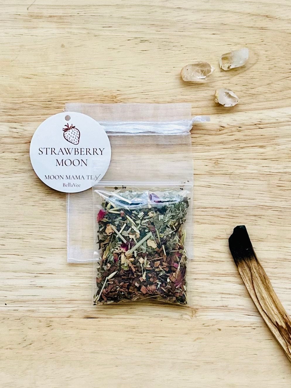 Tea packet and drawstring pouch styled next to clear quartz crystals.