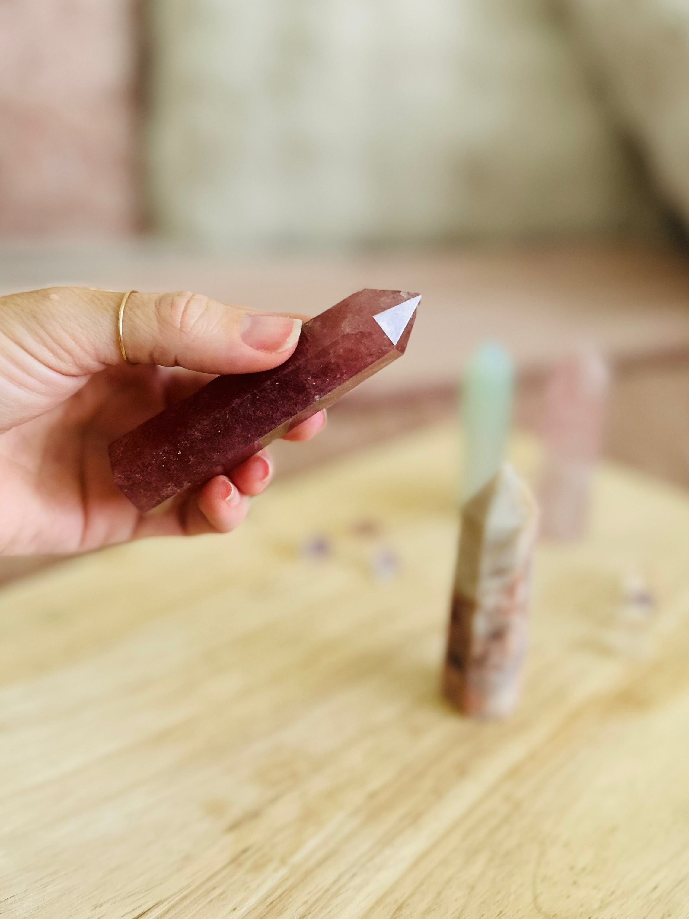 Hand holding crystal point with soft pink background