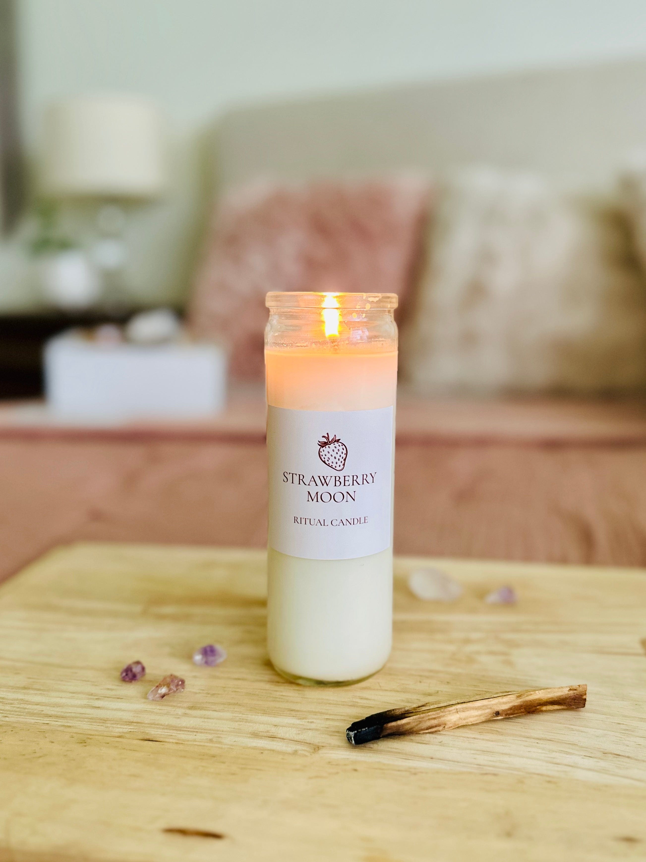 Crystal candle lit beside ritual tools and dried botanicals for full moon ceremony.