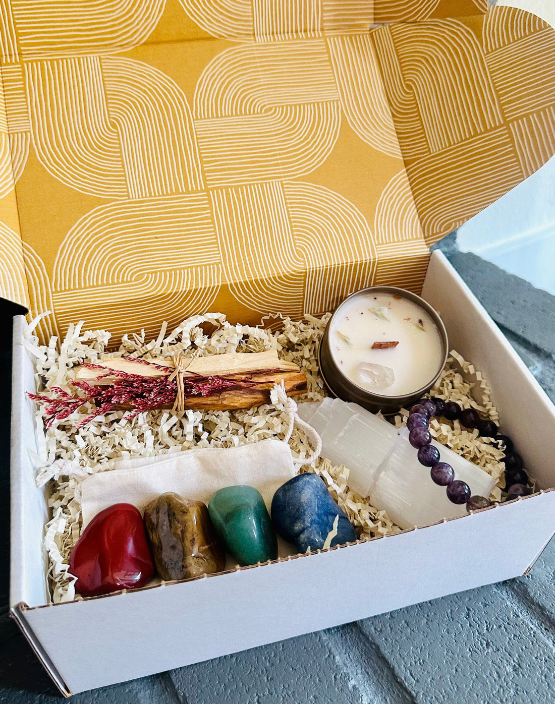 Crystal Wellness Gift Box with Blue Lapis, Green Aventurine, Brown Jasper, Red Jasper, Selenite Tower, Palo Santo bundle, mini crystal candle, and Amethyst bracelet.