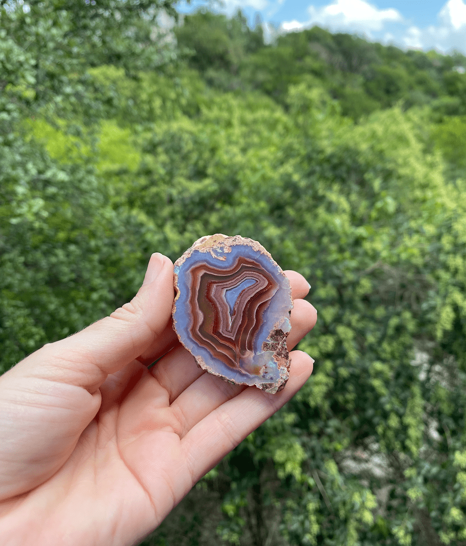 Banded Brazilian Agate slice with vibrant blue, purple, gold, and red hues, featuring translucent Quartz lining and natural edges.