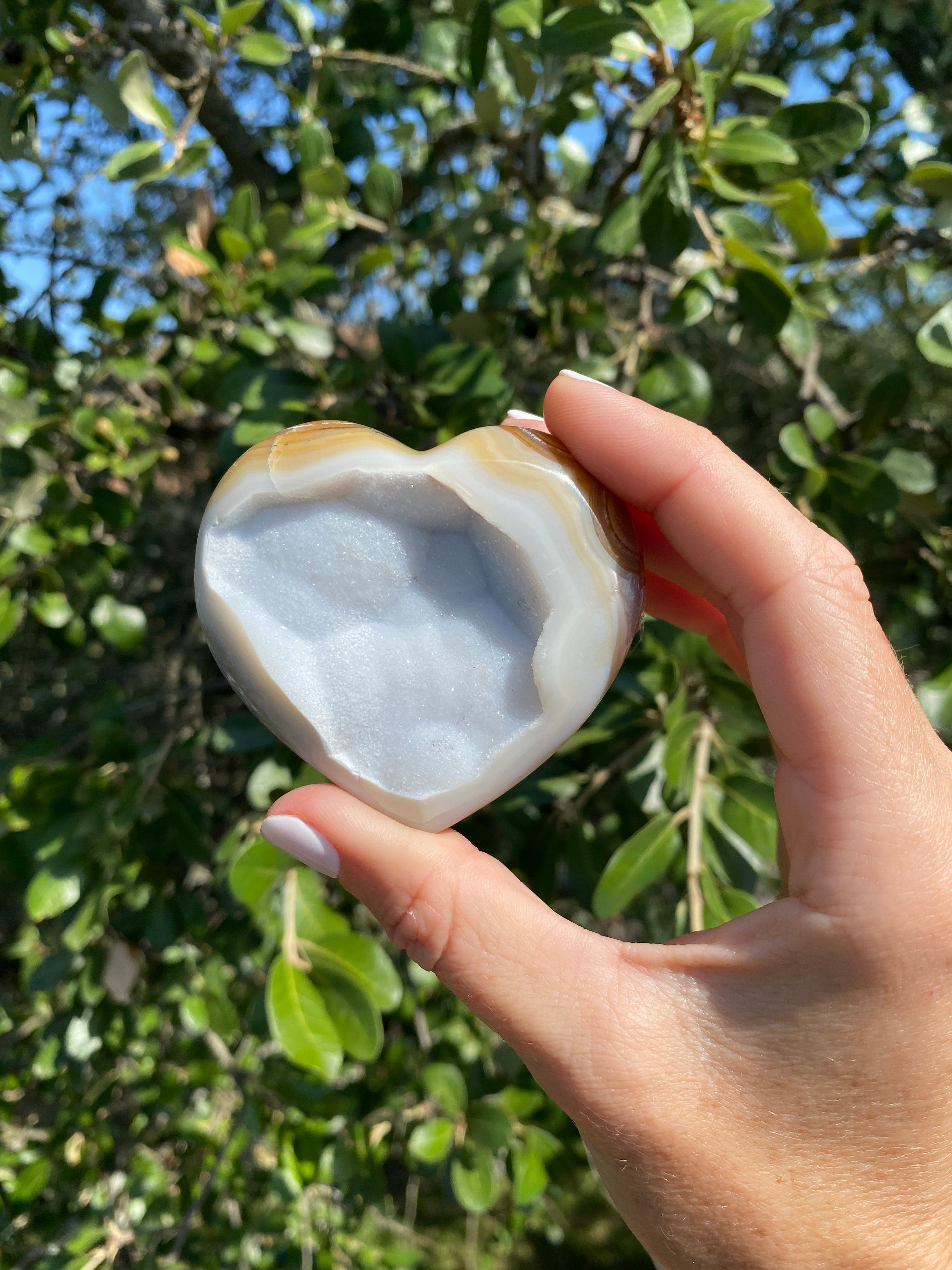 Held up close, the Snow White Agate Heart reveals stunning gold, tan, and cream bands, with shimmering gold glitter throughout its backing