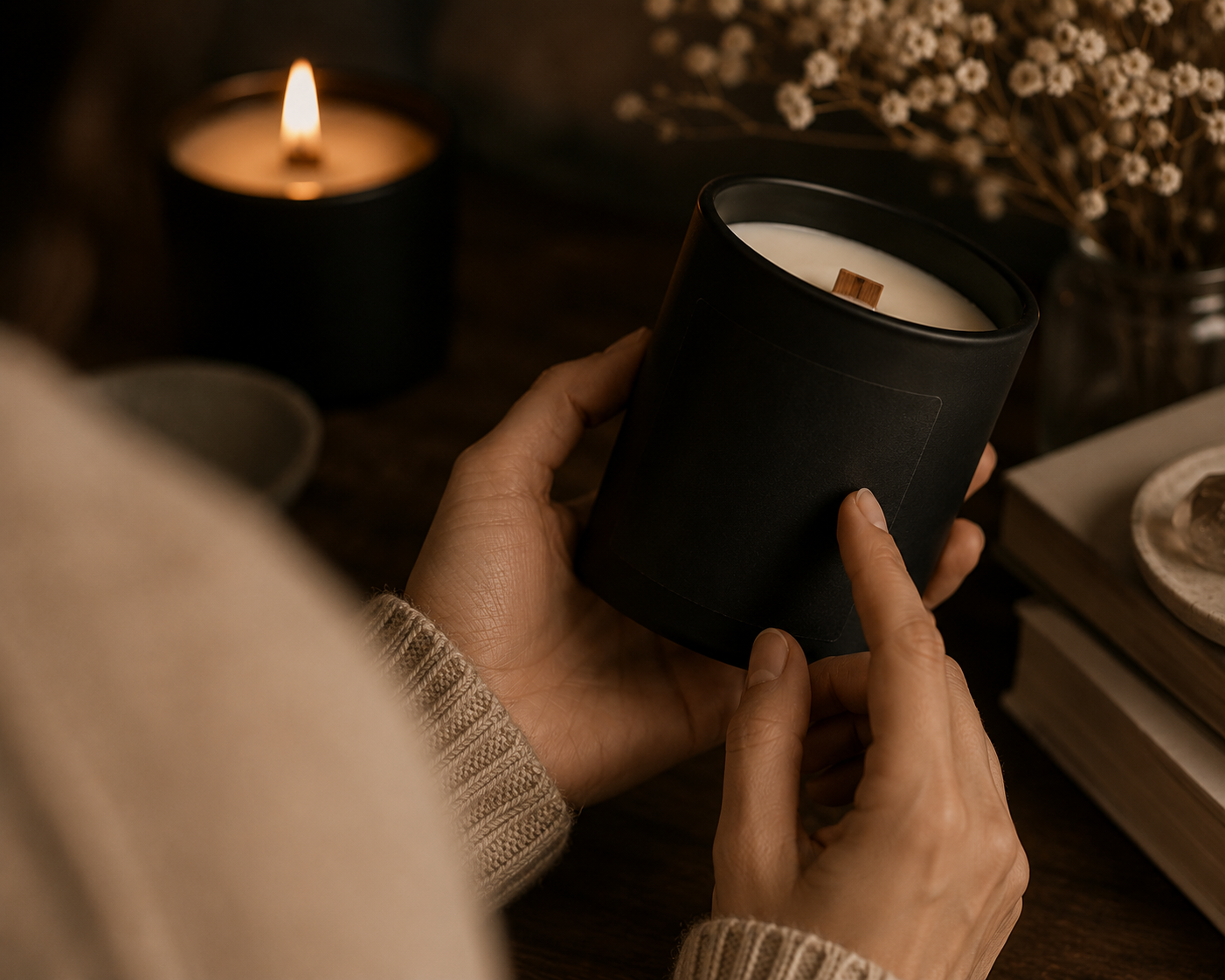 Person examining a non-toxic candle label in a matte black vessel with a wooden wick. Warm candlelight and natural ingredients highlight what to look for when choosing a clean-burning candle made with coconut wax and safe fragrance oils.
