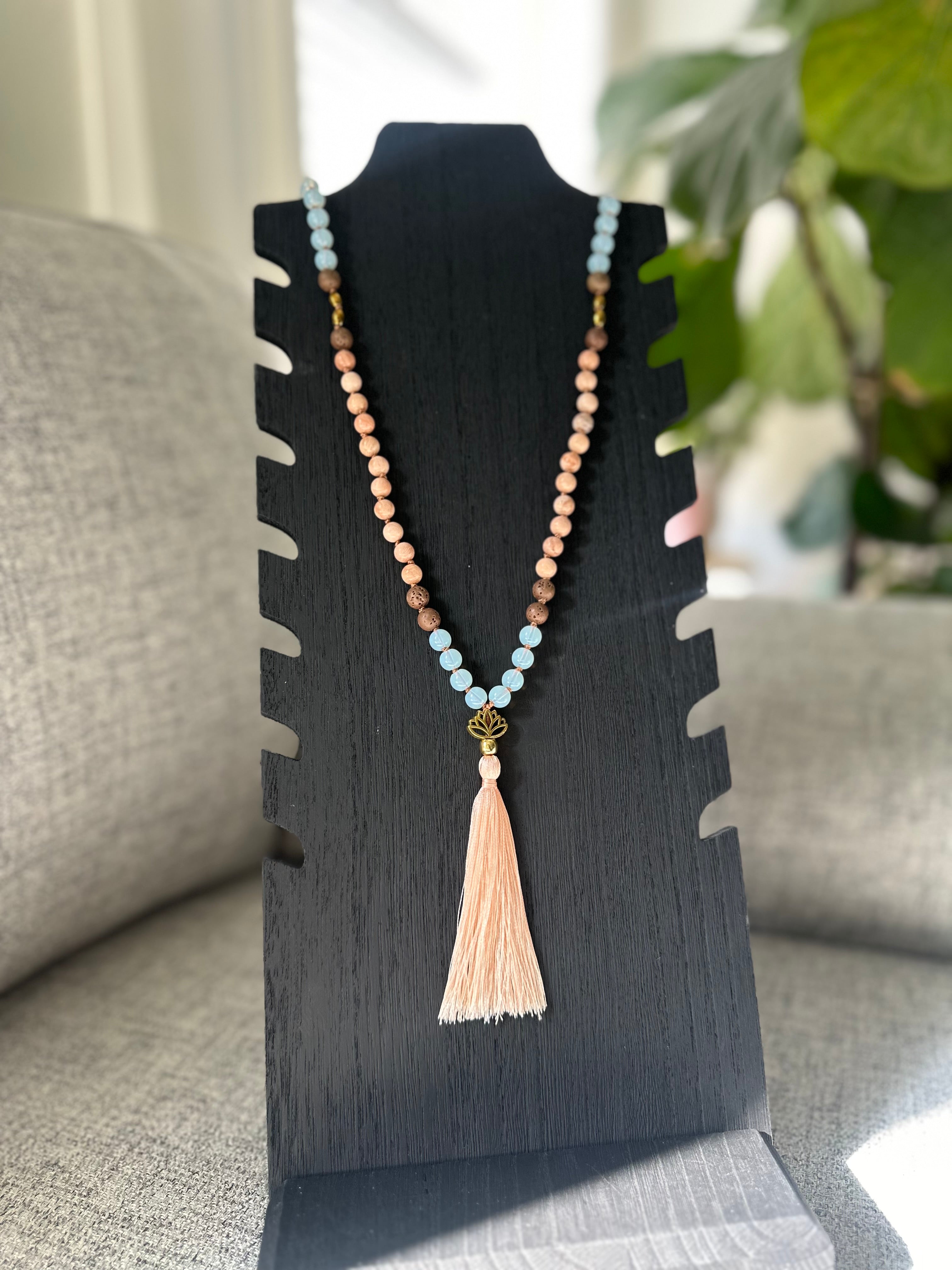 The Goddess Powerhouse Mala, with Peach Moonstone, Opalite, Lava, and Gold Hematite beads, is a beautifully crafted piece for peace and grounding