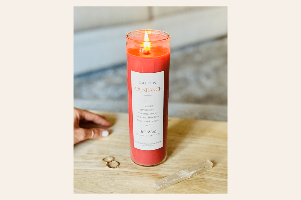Tall Abundance ritual candle with a label on a wooden surface