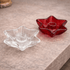 Two star-shaped glass candle holders, one clear and one red, on a stone surface.