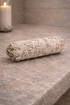 Rolled sage smudge stick on a stone surface with a blurred candle in the background