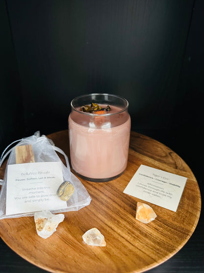 Pink crystal candle on a wooden table with crystals and cards on a dark background