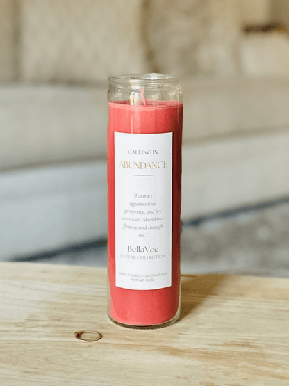Close-up of the Calling In: Abundance Ritual Candle in a bold red wax with white label.