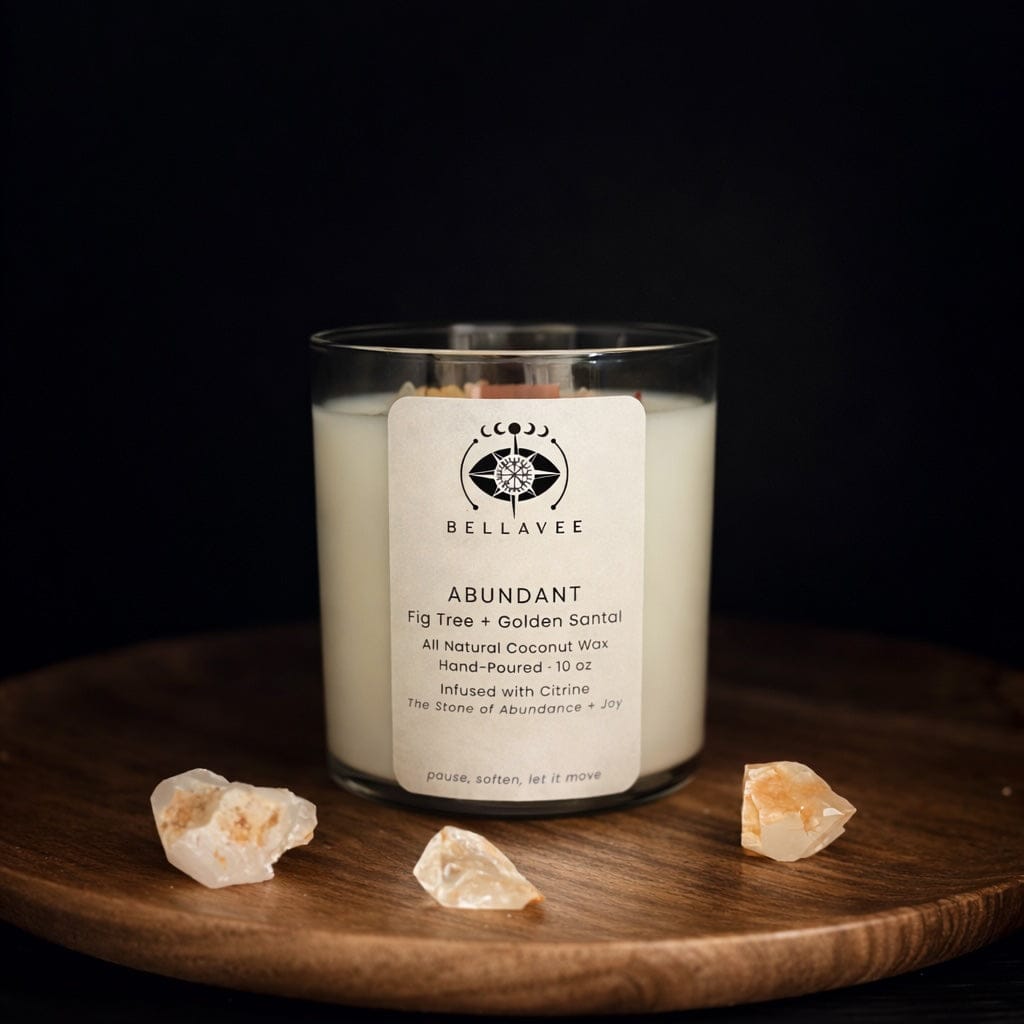 Hand-poured Abundant ritual candle in a clear glass vessel infused with citrine crystals, styled on a wooden surface against a dark background.