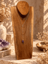 Raw Amethyst infinity drop necklace with gold chain displayed on wooden jewelry stand