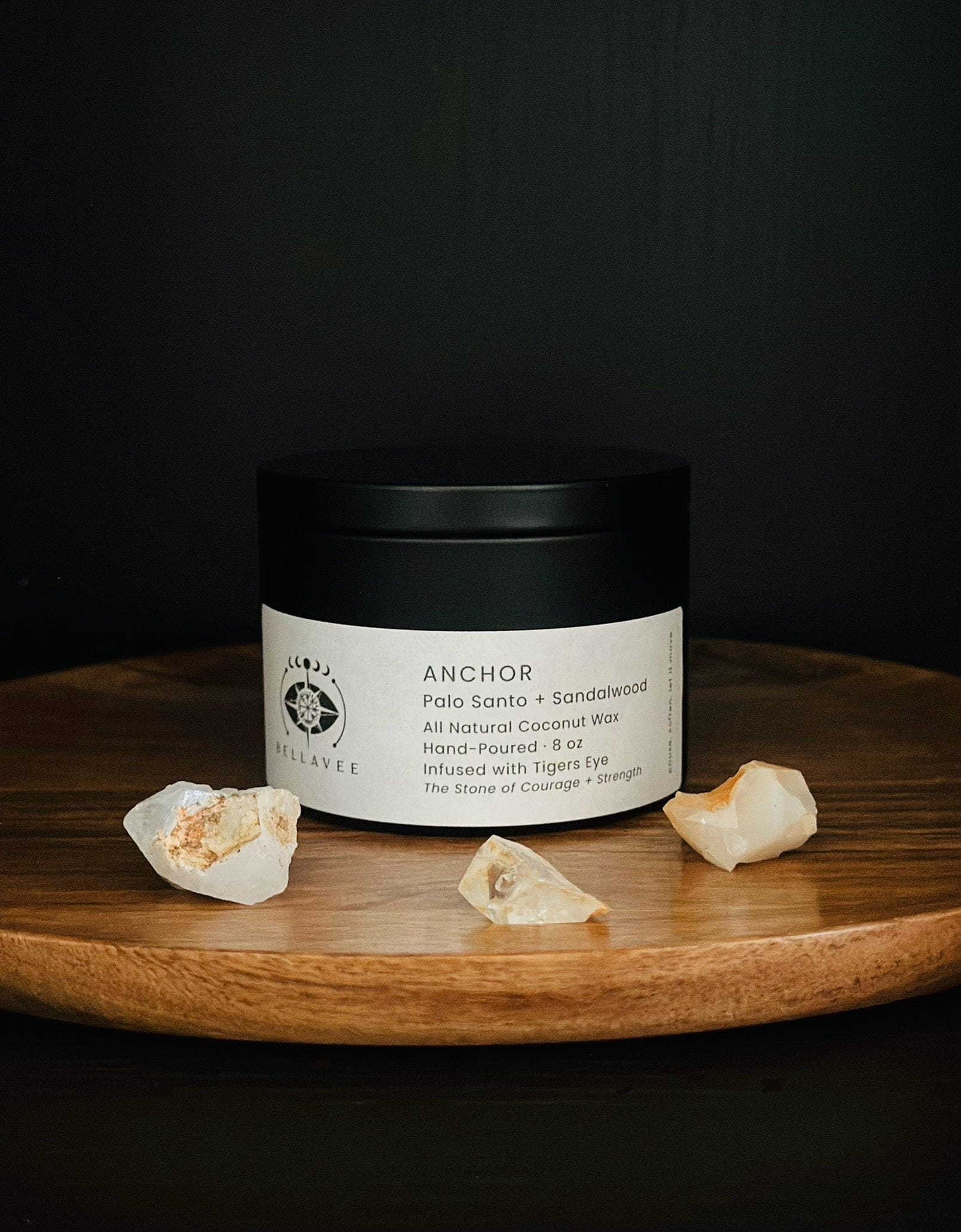 Anchor Tiger’s Eye crystal candle tin on wooden surface with grounding aesthetic on wooden tray with crystals and dark background.