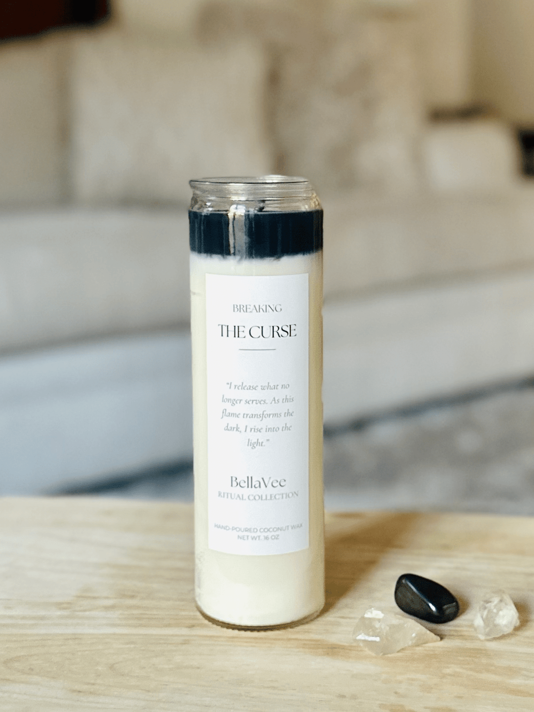 Close-up of the Breaking The Curse Ritual Candle with black and ivory wax in a clear glass container.
