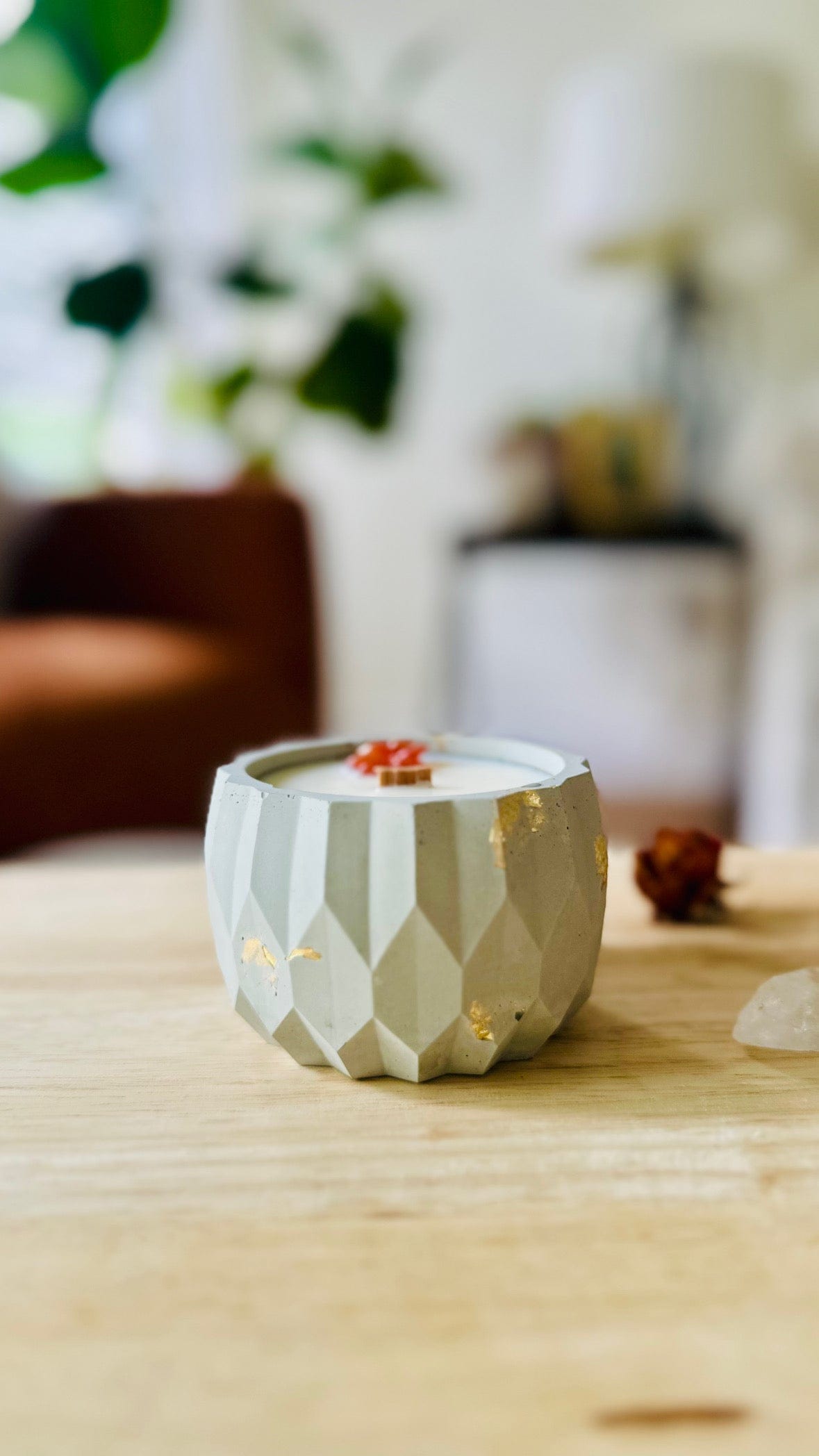 Handmade cement candle with gold flecks and wooden wick on a stone surface