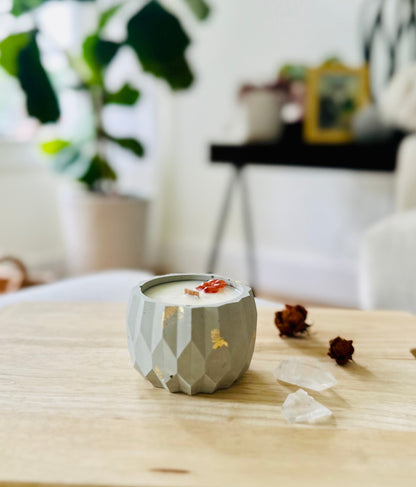 Textured cement candle with gold flecks and crystal accent, surrounded by natural light and calming tones.
