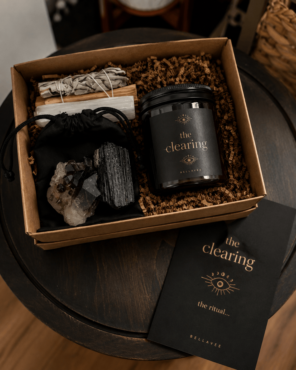 BellaVee THE CLEARING Energetic Eviction Ritual Kit with amber crystal candle, smoky quartz, black tourmaline, sage, palo santo, selenite, and ritual card.