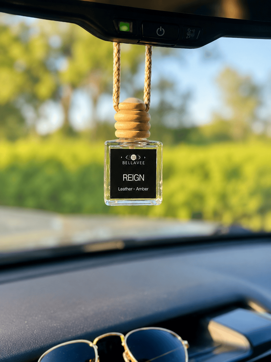 BellaVee REIGN car diffuser hanging from a rearview mirror with a leather and amber fragrance. Handcrafted non-toxic car air freshener with a luxury scent designed for grounding, confidence, and intentional living