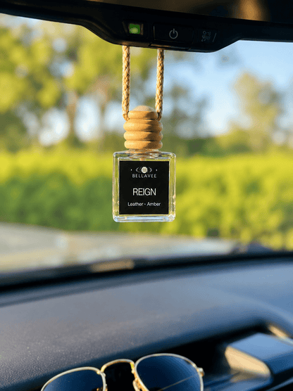 BellaVee REIGN car diffuser hanging from a rearview mirror with a leather and amber fragrance. Handcrafted non-toxic car air freshener with a luxury scent designed for grounding, confidence, and intentional living