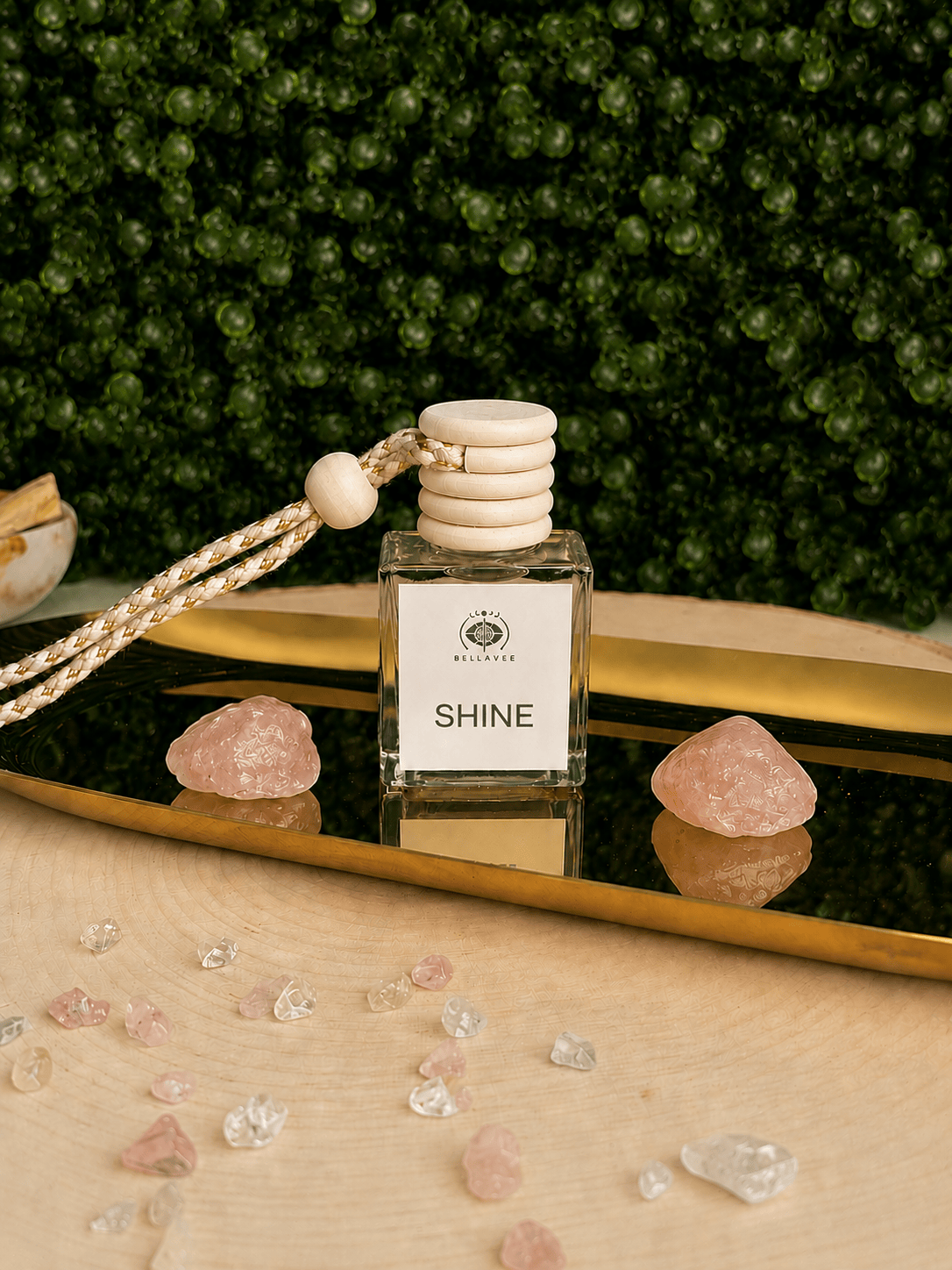 OY non-toxic car diffuser by BellaVee, glass bottle with wood cap and hanging rope, styled with rose quartz on a mirrored tray
