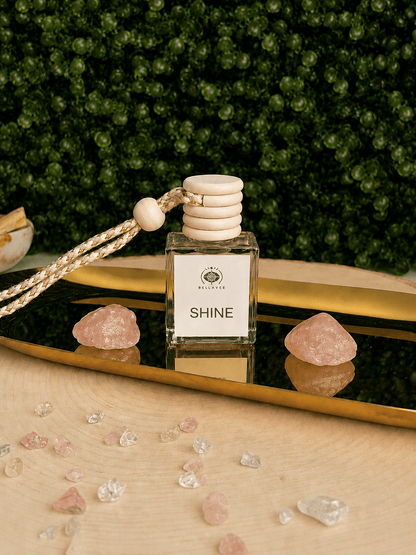 OY non-toxic car diffuser by BellaVee, glass bottle with wood cap and hanging rope, styled with rose quartz on a mirrored tray