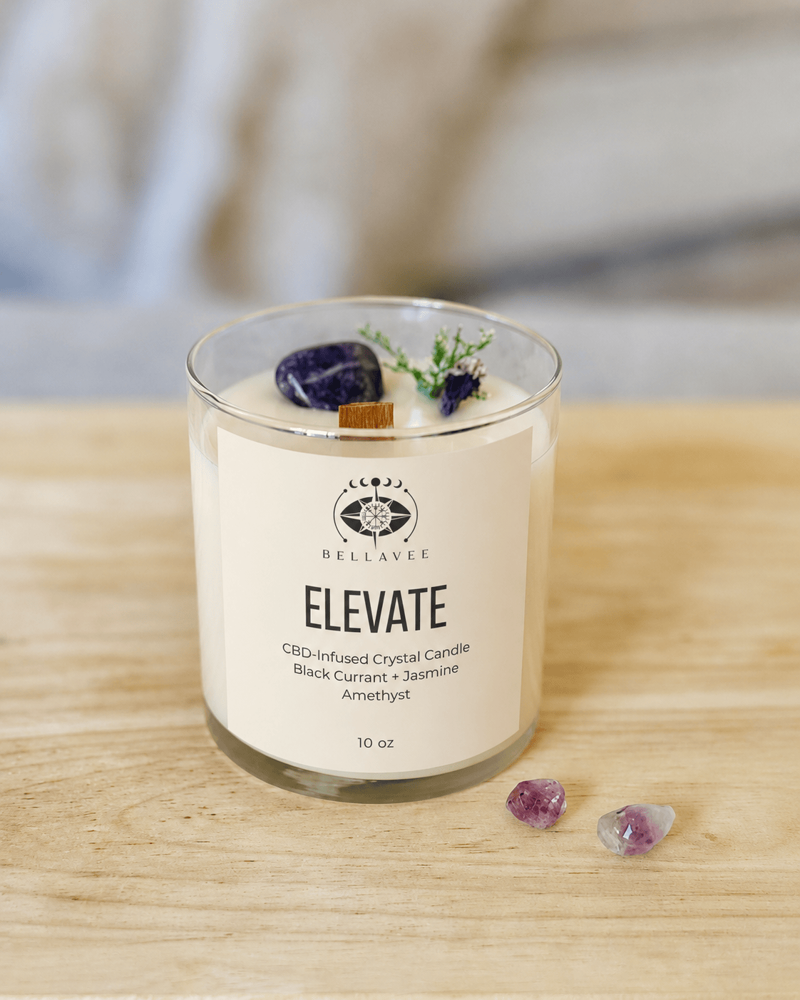 BellaVee ELEVATE CBD crystal candle featuring black currant and jasmine scent, amethyst crystal, botanical accents, and a wooden wick in a clear glass vessel.