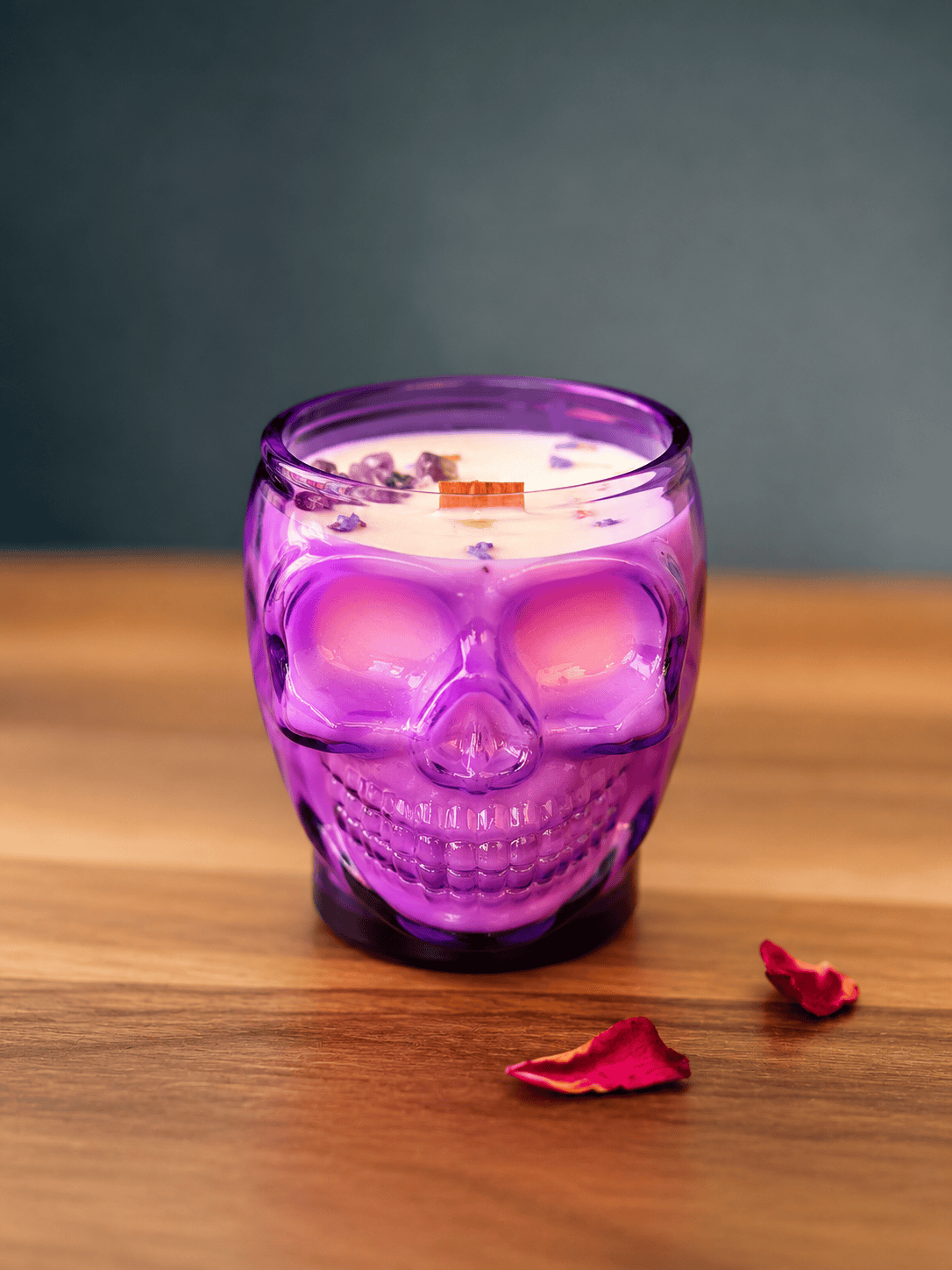 Purple skull-shaped candle on a wooden surface with a dark background