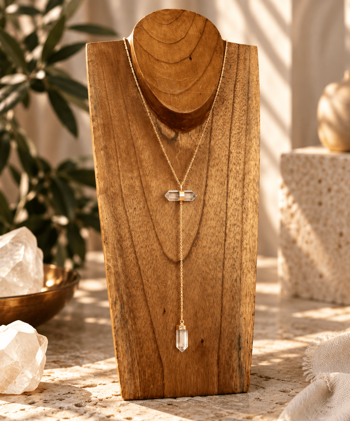 Clear Quartz two-stone Y-drop necklace with gold chain displayed on wooden jewelry stand