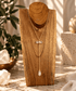 Clear Quartz two-stone Y-drop necklace with gold chain displayed on wooden jewelry stand