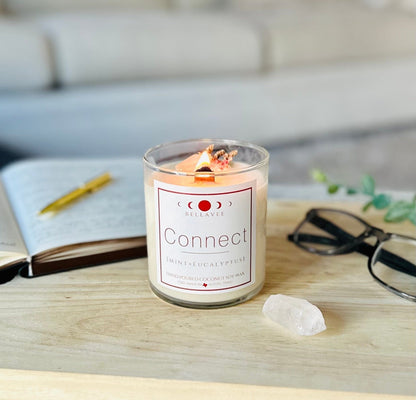 Lit Connect CBD Crystal Candle glowing with warm light, placed on a tabletop next to clear quartz and wellness items, evoking a calming aromatherapy ritual.