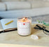 Lit Connect CBD Crystal Candle glowing with warm light, placed on a tabletop next to clear quartz and wellness items, evoking a calming aromatherapy ritual.