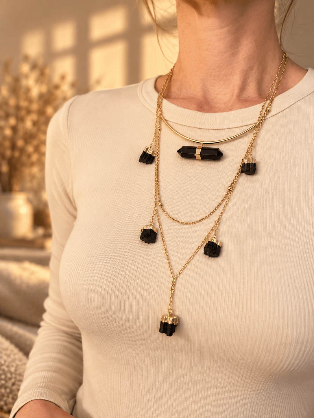 Curved bar crystal necklace worn as part of a layered gold crystal necklace stack