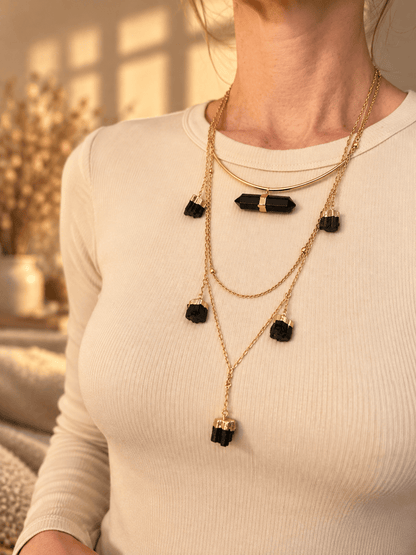 Curved bar crystal necklace worn as part of a layered gold crystal necklace stack