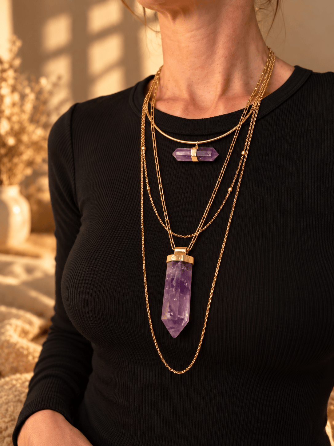 Curved bar crystal necklace worn as part of a layered gold crystal necklace stack