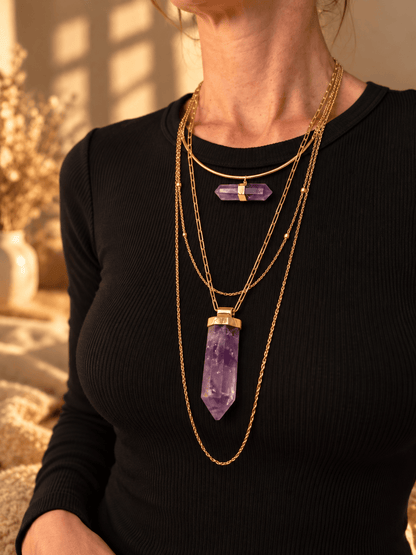 Curved bar crystal necklace worn as part of a layered gold crystal necklace stack
